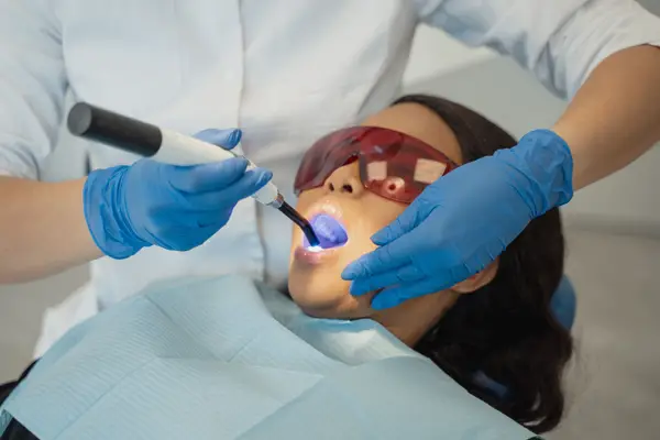 A dentist setting a tooth-coloured filling with a curing light