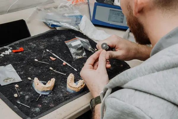 A dental technician shaping crowns on models in a laboratory