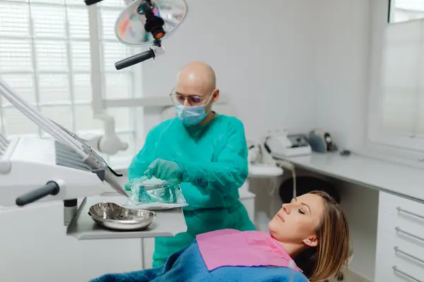 An oral surgeon preparing to treat a patient in a dental chair