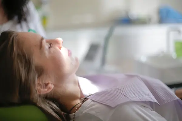 A patient resting calmly in a dental chair with her eyes closed