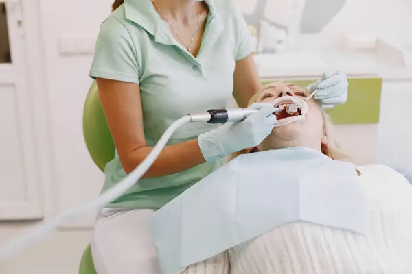 A dental hygienist cleaning a patient's teeth with an ultrasonic scaler